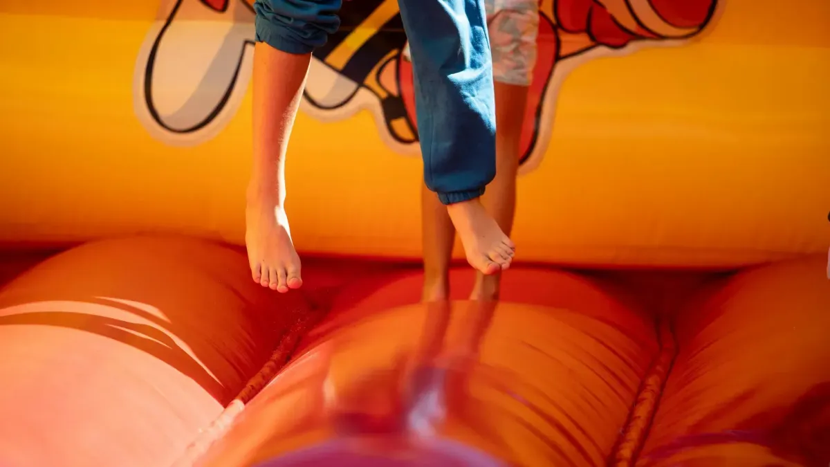 Kids jumping in an orange bouncy castle.